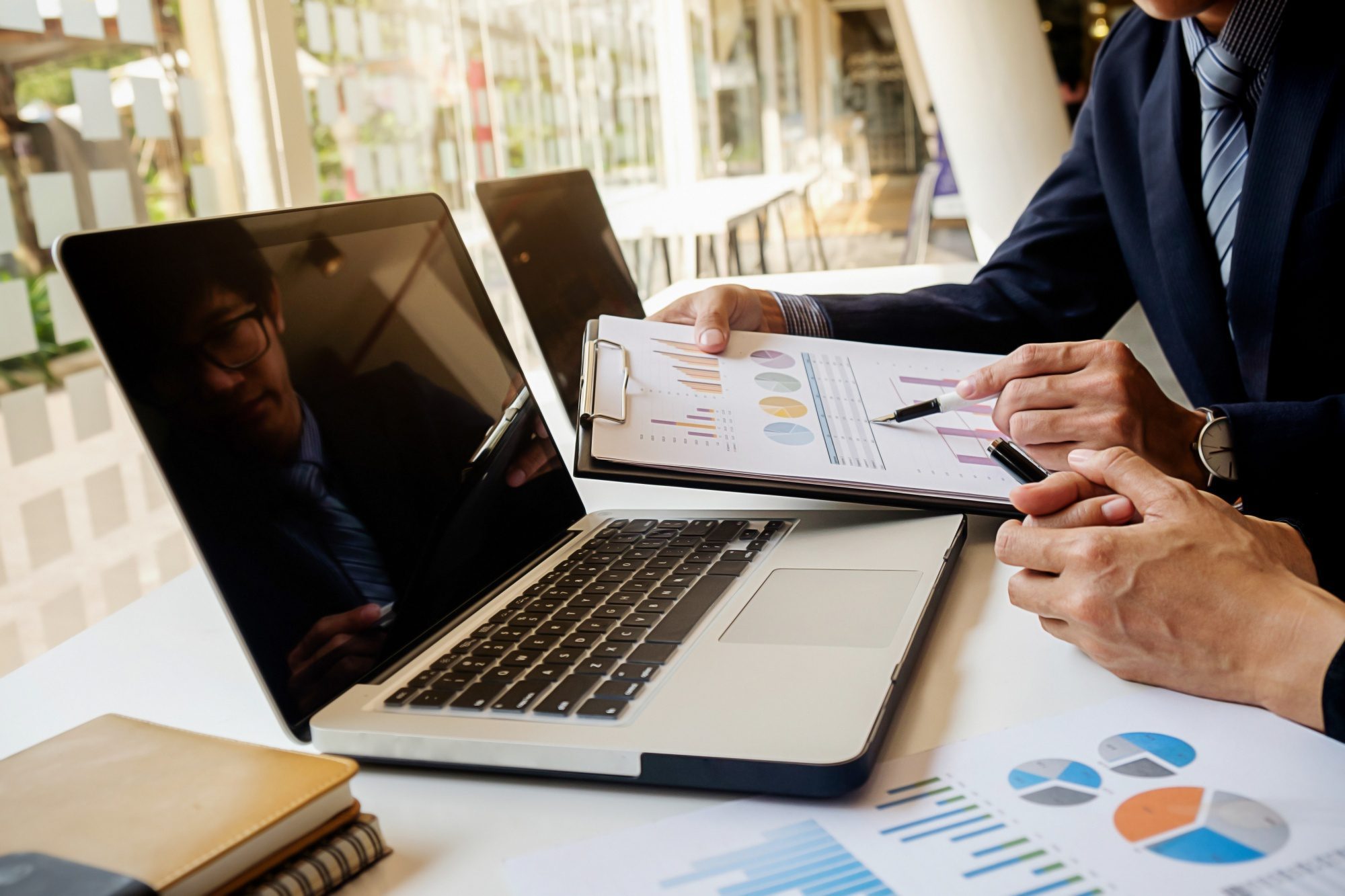 Business professionals discussing charts on laptop