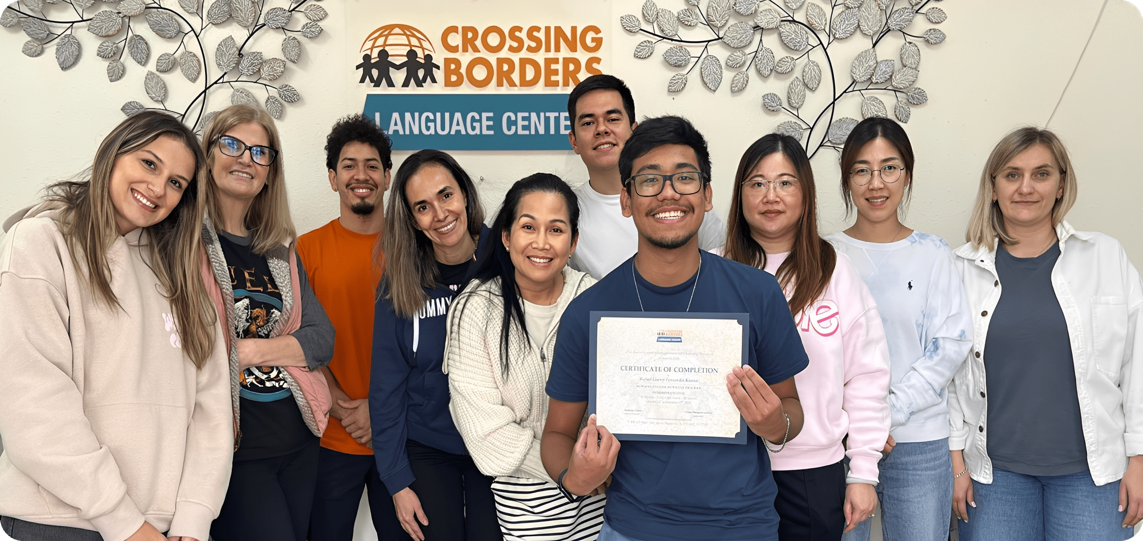 Smiling language students holding certificate at center